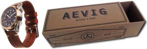 Een sfeerfoto van een luxe herenhorloge naast een op maat gemaakte schuifdoos van stevig bruin kraft karton. Het horloge heeft een klassieke uitstraling met een bruine lederen band en een bronzen kast. De bijbehorende verpakking is een bedrukte schuifdoos waarbij de binnenkant naar rechts is uitgeschoven. De huls van de doos is voorzien van een gedetailleerde zwarte bedrukking in een vintage stijl met de merknaam 'AEVIG WATCHES & MORE', aangevuld met teksten als 'Since 2013' en 'Trade Mark'. Het gebruik van door en door bruin kraft karton voor deze horlogeverpakking benadrukt de combinatie van een natuurlijke, eco-vriendelijke uitstraling en een hoogwaardig, professioneel design. Dit type verpakking op maat biedt optimale bescherming en een onderscheidend vermogen voor exclusieve lifestyle-producten.