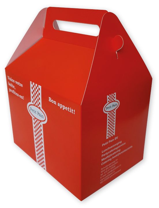 doos met handvat voor lunchpakket Een felrode, kartonnen doos met handvat, specifiek op maat gemaakt voor 'Petit Pain' als verpakking voor een maaltijd of lunchpakket. De doos heeft een schuin toelopende bovenkant die uitmondt in een stevig, geïntegreerd handvat met een horizontale uitsparing voor optimaal draaggemak. De witte bedrukking op de rode achtergrond bevat de tekst 'Bon appetit!' en de Franse vertaling 'Voici votre boîte, profitez-en!'. Aan de zijkant is een verticaal rood-wit geblokt lint afgebeeld met het 'Petit Pain' logo, aangevuld met bedrijfsgegevens zoals adres, telefoonnummer en website. Deze individuele maaltijdverpakking is gemaakt van voedselveilig karton en illustreert hoe een bedrukte box met logo en pakkende tekst kan worden ingezet voor catering of partyverhuur om een merk onder de aandacht te brengen.