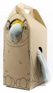 Een professionele, op maat gemaakte speelgoeddoos van milieuvriendelijk bruin kraftkarton, specifiek ontworpen voor de 'Mamagaai' knuffel. De doos heeft een uniek ontwerp in de vorm van een vogelhuisje met een handig handvat aan de bovenzijde. Op de voorzijde is een minimalistische zwarte lijntekening van een vogel gedrukt die de contouren van de knuffel volgt. De verpakking is voorzien van strategische uitsparingen (vensters): door een rond gat aan de bovenkant steekt de snavel en de gele kuif van de blauwe knuffel naar buiten, en aan de zijkant komt een vleugel door een opening. Dit interactieve ontwerp met venster maakt de klant direct nieuwsgierig naar de zachte inhoud en presenteert het product op een aantrekkelijke en professionele wijze.