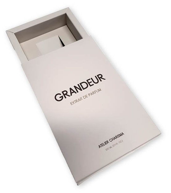 bedrukte parfumdoos schuifdoos ladedoos met interieur voor 100 ml parfumfles bedrukt in full color met logo gelamineerd Een close-up van een strakke, moderne, open schuifdoos voor een parfumflesje, die een extreem premium uitstraling en de kwaliteit van verpakkingen met interieur benadrukt. Type Verpakking: Het betreft een schuifdoos of ladedoos van hoogwaardig karton. De lade is gedeeltelijk uit de sleeve geschoven. Design en Uitstraling: De verpakking is uitgevoerd in een minimalistische, elegante lichte kleur (mogelijk wit of zeer lichtgrijs) en is gelamineerd, wat bijdraagt aan de luxe en premium uitstraling. De opdruk is strak en helder in een donkere kleur. Merkdetails: Prominent op de sleeve staat de productnaam 