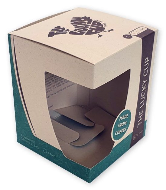 Een milieuvriendelijke productverpakking voor de 'The Lucky Cup' koffiebeker van Coffee Based. Dit vierkante doosje met venster is vervaardigd uit duurzaam Paperwise karton, gemaakt van landbouwafval, wat goed zichtbaar is door de natuurlijke, gespikkelde textuur van het materiaal. Het doosje heeft een groot, op maat gemaakt venster zonder folie dat over de hoek doorloopt, waardoor de klant de koffiebeker (gemaakt van koffie-afval) direct kan zien en de unieke textuur kan aanraken. De verpakking is bedrukt met een stijlvol donkerblauw logo van een vogel op de bovenzijde en de tekst 'Made from Coffee' in een cirkel op de zijkant. Met een formaat van 92 x 92 x 133 mm is dit een perfect voorbeeld van een gepersonaliseerde vensterdoos die de juiste uitstraling geeft aan een authentiek en milieuvriendelijk product.