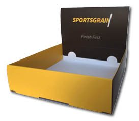 Een strak vormgegeven, op maat gemaakte displaydoos van sulfaatkarton voor Sportsgrain, ideaal als toonbank display of balie display. De display box heeft een moderne uitstraling met een felgele voorzijde en contrasterende donkerbruine zijkanten en achterwand. Op de opstaande achterzijde staat het logo 'SPORTSGRAIN' in geel en wit, met daaronder de motiverende slogan 'Finish First'. Deze duurzame presentatieverpakking heeft een formaat van 180 x 210 x 50 mm en is afgewerkt met een luxe mat laminaat, wat zorgt voor een professionele uitstraling en extra aantrekkingskracht op de toonbank bij de presentatie van sportbrood.