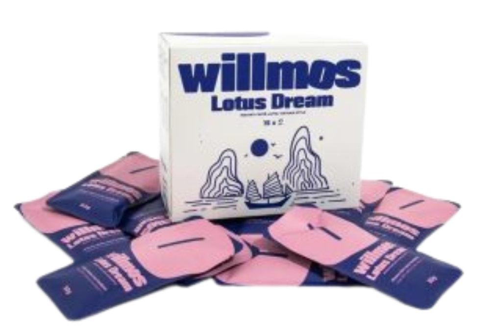 Een stevig, wit bedrukt autolock doosje voor Willmos Lotus Dream coffee met een matte afwerking door matlaminaat. Het doosje staat afgebeeld met verschillende roze en blauwe sachets of zakjes oploskoffie. De verpakking is voorzien van een blauwe bedrukking met een oosterse illustratie van bergen en een zeilschip. Dit doosje op maat (172 x 78 x 150 mm) is een voorbeeld van een functionele productverpakking met een tear strip opening voor gebruiksgemak. De autolock bodem zorgt ervoor dat het doosje snel en efficiënt kan worden opgezet voor het verpakken van de zakjes koffie.