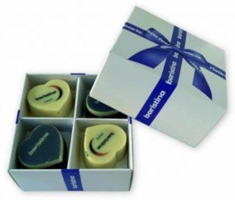 Close-up van een kleine, witte, vierkante giftset of cadeaudoos met los deksel die perfect is als doosje voor kaarten of bonbons. Het deksel, dat is versierd met een glanzend blauw satijnen lint en strik, is van de onderdoos geschoven en staat rechtsboven, schuin geplaatst ten opzichte van de onderdoos. Het blauwe lint is bedrukt met het woord 