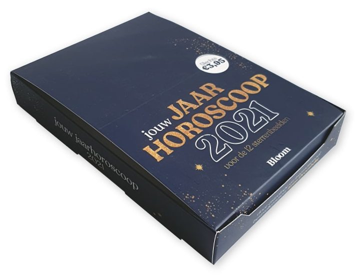 Een professioneel bedrukte displaydoos op maat gemaakt voor 'Bloom' uit België, getoond in gesloten toestand als Retail Ready Packaging (RRP). De display box heeft een luxe uitstraling met een donkerblauwe achtergrond, bedrukt met gouden sterren en de tekst 'jouw JAARHOROSCOOP 2021 voor de 12 sterrenbeelden'. De bovenzijde is voorzien van een ronde prijsaanduiding 'Slechts €3,95'. Deze compacte toonbank display van 151 x 215 x 34 mm is uitgevoerd in full-color bedrukking met laminaat en dient als stevige verzendverpakking die direct als baliedisplay in de winkel kan worden geplaatst om impulsaankopen van A5-boekjes te stimuleren.