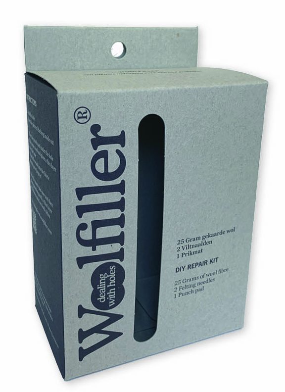 Een professioneel bedrukt hangend doosje met venster voor de Woolfiller DIY Repair Kit, uitgevoerd in een natuurlijke grijze tint van gerecycled grijskarton. De verpakking heeft een verticaal, ovaalvormig venster zonder folie aan de voorzijde, waardoor de inhoud van de reparatieset direct zichtbaar is voor de klant. Het doosje is voorzien van een stevig kopstuk met een rond gat (ophangoog) om als hangverpakking geordend aan een haak in de winkel te presenteren. Op de voorzijde staat het 'Woolfiller' logo verticaal gedrukt, samen met een opsomming van de inhoud: 25 gram gekaarde wol, 2 viltnaalden en 1 prikmat. Deze functionele productverpakking is ontworpen om de klant te verleiden en staat in een winkelrek altijd met de voorzijde naar de klant toe voor maximale attentiewaarde.
