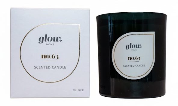 Luxe witte vierkante doos voor kaarsen met een minimalistisch en modern design, uitgevoerd met een hoogwaardige goudfolie bedrukking voor een exclusieve uitstraling. De verpakking staat naast een bijbehorende donkergroene glazen geurkaars, waarbij zowel de doos als de kaarshouder zijn voorzien van het verfijnde 'glow. HOME no.63 scented candle' logo binnen een elegante goudkleurige druppelvorm. Deze op maat gemaakte geschenkdoos van Bedrukte-doosjes.nl is specifiek ontwikkeld voor een inhoud van 380 gram en dient als het ideale voorbeeld van een premium kaarsenverpakking voor high-end interieurmerken, waarbij stevigheid en esthetiek worden gecombineerd voor een optimale unboxing ervaring. Gerukaars in glas,