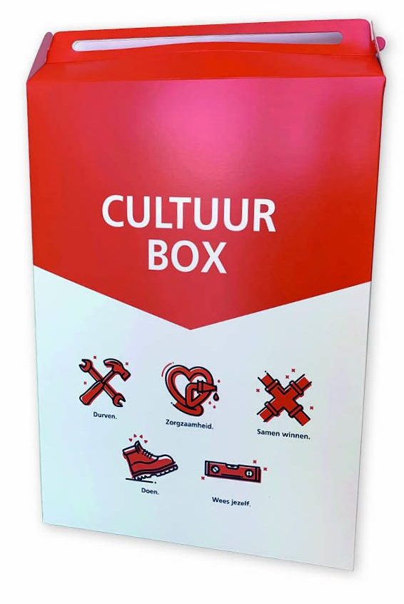 Een grote, rechthoekige 'Cultuur Box' op A3-formaat, uitgevoerd als een gesloten doos met handvat en een opvallende full color bedrukking. De bovenste helft van de doos is helderrood met de tekst 'CULTUUR BOX' in witte hoofdletters; de onderste helft is wit en toont vijf rode iconen met bijbehorende teksten zoals 'Durven', 'Zorgzaamheid' en 'Samen winnen'. De verpakking is gemaakt van hoogwaardig vouwkarton met een gladde afwerking voor een premium uitstraling. Dit model is een voorbeeld van een gepersonaliseerd welkomstpakket of goodie bag, ideaal voor het verpakken van grotere cadeaus of kleding bij events.