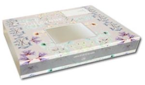 Een luxe bedrukte kartonnen sleeve (schuifhuls) voor een diepvriesmaaltijd, gemaakt van stevig hardsized GC2 karton. De sleeve heeft een lichtgrijze achtergrond met een elegant botanisch patroon van bloemen en planten in zachte pastelkleuren zoals lila, mintgroen en blauw. In het midden van de bovenzijde zit een uitgesneden rechthoekig venster waardoor de maaltijd in het onderliggende bakje deels zichtbaar blijft. De zijkant is bedrukt met een website-URL, wat bijdraagt aan de merkidentiteit. Deze vochtbestendige verpakking is speciaal ontworpen voor gebruik in de vriezer en koeling, biedt een professionele uitstraling voor kant-en-klaarmaaltijden en is volledig recyclebaar via het oud papier.