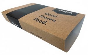 Een horizontaal gefotografeerde kartonnen sleeve voor diepvriesmaaltijden van het merk Suppr., uitgevoerd in een authentiek bruin kraft karton met een ambachtelijke uitstraling. De schuifhuls is bedrukt met zwarte tekst 'Good Frozen Food.' en bevat het logo van Suppr. op de bovenkant en zijkant. Een brede zwarte baan loopt over de linkerzijde van de sleeve als onderdeel van het moderne ontwerp. De verpakking is vervaardigd van hardsized (HS) karton, waardoor deze voedselveilig, condensbestendig en vochtbestendig is voor gebruik in de vriezer of koeling zonder in te zakken. De sleeve is aan de zijkanten open, bedoeld om strak om een maaltijdbakje te schuiven, wat zorgt voor een professionele presentatie en versterking van de merkidentiteit. Op de onderste rand staat de website 'www.suppr.nl' vermeld. Het materiaal is volledig recyclebaar en mag na gebruik bij het oud papier.