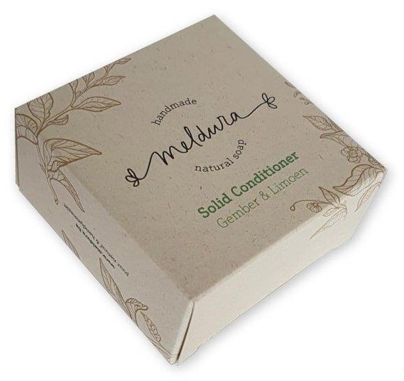 Deze afbeelding toont een verfijnde verpakking voor een Solid Conditioner bar van het merk Meldura, waarbij de keuze voor materiaal de duurzame missie van het merk versterkt. Het doosje is vervaardigd uit PaperWise hardsized karton, een revolutionair materiaal gemaakt van stengels en bladeren die overblijven na de oogst (landbouwafval). Dit maakt de verpakking volledig boomvrij en geeft het karton een subtiele, natuurlijke vezelstructuur die perfect past bij de botanische lijntekeningen van gember en limoen. Omdat conditioner bars vaak in vochtige badkameromgevingen staan, biedt de 'hardsized' afwerking van het PaperWise materiaal de nodige barrière tegen waterdamp en oliën. Hierdoor blijft de verpakking stevig en de bedrukking haarscherp, zonder dat er een plastic laminaat aan te pas komt. Dit zeepdoosje is een schoolvoorbeeld van hoe moderne haircare-merken kunnen kiezen voor een 100% circulaire en plasticvrije presentatie met een minimale ecologische voetafdruk.