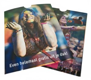 Set van twee op maat gemaakte giftcard sleeves in a6 formaat (insteekmapjes) van hoogwaardig sulfaatkarton, voorzien van een levendige full-color bedrukking met festival-fotografie. De hoesjes zijn aan drie zijden gesloten en hebben aan de bovenzijde een halfronde vingeruitsparing (duimgreep) voor het eenvoudig in- en uitschuiven van een cadeaubon of pasje. De voorzijde toont de tekst 'Even helemaal gratis uit je dak!' in een strak wit font op een donkere tekstbalk, geproduceerd door Drukkerij Van der Louw
