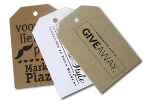 Drie rechthoekige hangtags met schuine hoeken bovenin, gepresenteerd in een waaier op een witte achtergrond. Van links naar rechts: een bruin Kraft label met het logo van 'Market Place', een helderwit label voor 'Industriële en Retro meubelen' en een grijskartonnen label met de tekst 'Homemade Gifts Giveaway'. Alle labels zijn scherp bedrukt met zwarte inkt.