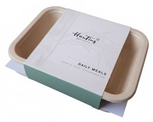 Witte kartonnen maaltijdsleeve met minimalistisch design, logo van HanTing Delivery en een subtiele grijze bamboe-illustratie. Deze duurzame wikkelverpakking voor daily meals is geproduceerd door Drukkerij Van der Louw in Berkel en Rodenrijs, leverbaar in kleine oplages vanaf 50 stuks voor horeca-startups tot 10.000+ stuks voor grootschalige catering in Nederland en België.