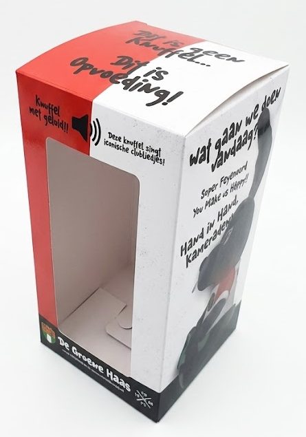 Een rechtopstaande, op maat gemaakte kartonnen speelgoedverpakking met een groot uitgestanst venster aan de voorzijde, gepresenteerd tegen een strakke witte achtergrond. De doos is bedrukt in een heldere rood-witte kleurstelling met speelse zwarte teksten en grafische illustraties. De zijkant toont een silhouet van een knuffel en verwijzingen naar geluidsfuncties, wat de interactieve eigenschappen van de inhoud benadrukt. Het ontwerp heeft een professionele afwerking met scherpe vouwlijnen en een stevige constructie, ideaal voor de presentatie van kinderproducten of promotionele artikelen in de retail. De verpakking combineert visuele aantrekkingskracht met functionele productbescherming.