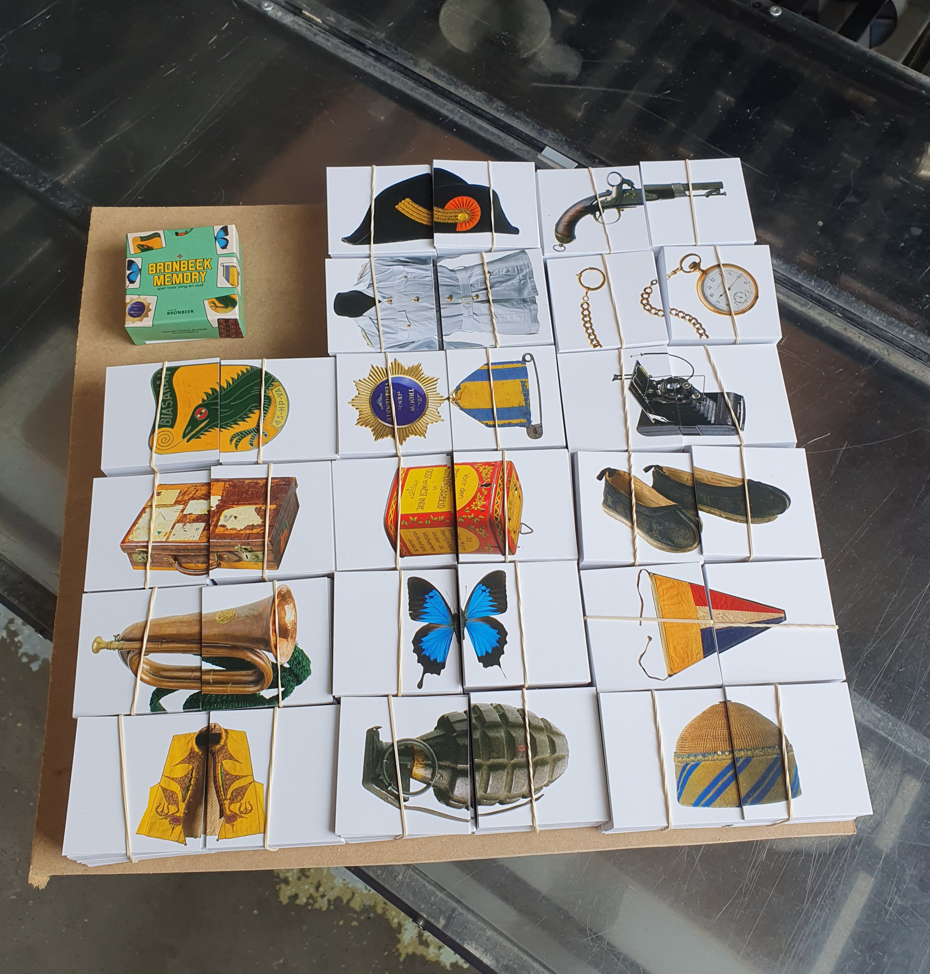 Productie van een doosje met kaartjes voor memoryspel met 32 kaartjes in de drukkerij van bedrukte-doosjes.nl in Berkel en Rodenrijs. De foto toont gestapelde, vers gestanste spelkaarten voor Museum Bronbeek op een werktafel, geproduceerd met onze eigen stansmachine. Duurzaam vakmanschap sinds 1966, waarbij precisie in stanswerk centraal staat voor zowel kleine oplages vanaf 50 stuks als grote volumes.