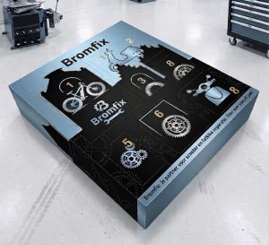 Luxe, op maat bedrukte adventsdoos met 8 vakjes als voorbeeld van een gepersonaliseerde adventskalender doos, ontworpen in de blauw-zwarte huisstijl van Bromfix en geproduceerd door Drukkerij Van der Louw. De vierkante kartonnen verpakking ligt in een werkplaats en toont een strakke nummering van 1 tot en met 8 op de bovenzijde, gecombineerd met grafische silhouetten van een fatbike, een scooter en technische tandwielen.