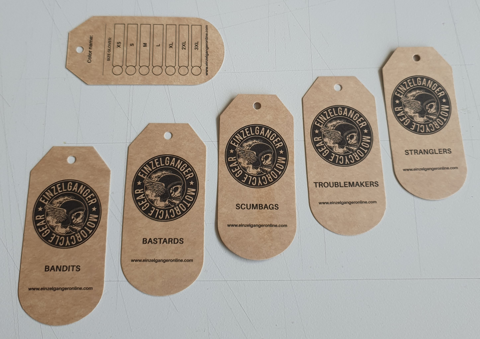 Bedrukte hangtags met logo in zwart van kraft karton, dubbelzijdig bedrukt en gestanst in speciale vorm. Einzelganger handschoenen.